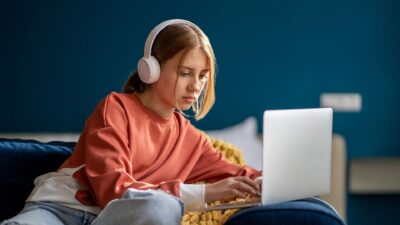 Teenage girl using laptop wearing headphones 2336680117