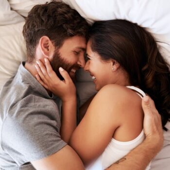 Young couple lying in bed embracing and laughing lifestyle