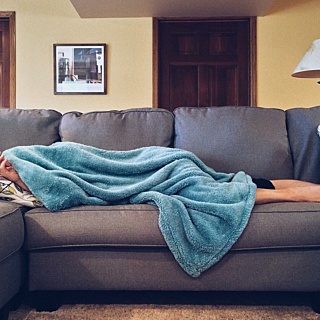Stock shock person on sofa with blanket